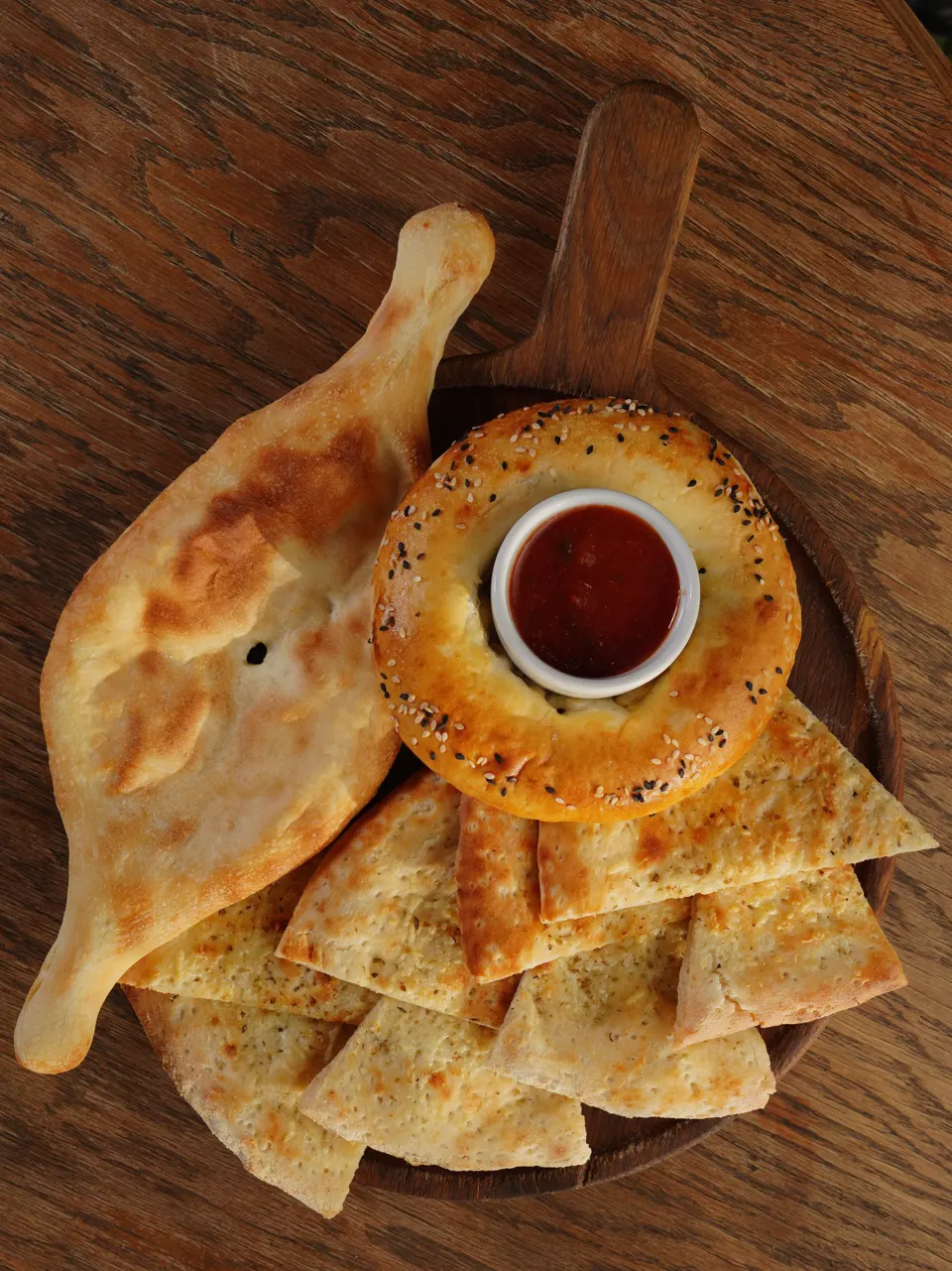 Georgian bread and cheese bread platter with red sauce on a wooden board
