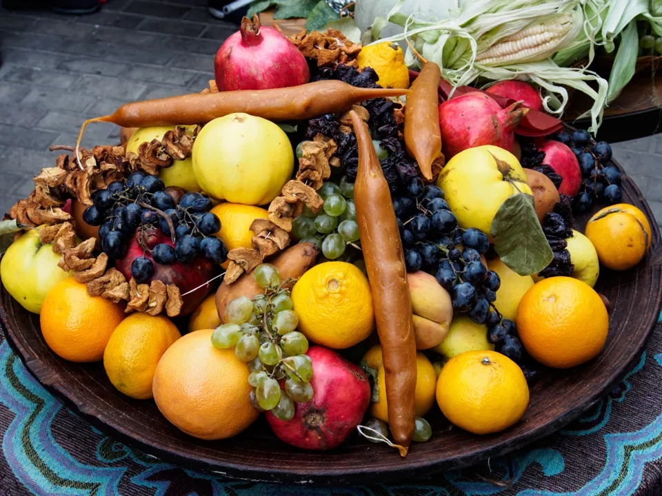 Georgian fruit platter with grapes, pomegranates, apples, oranges, and churchkhela