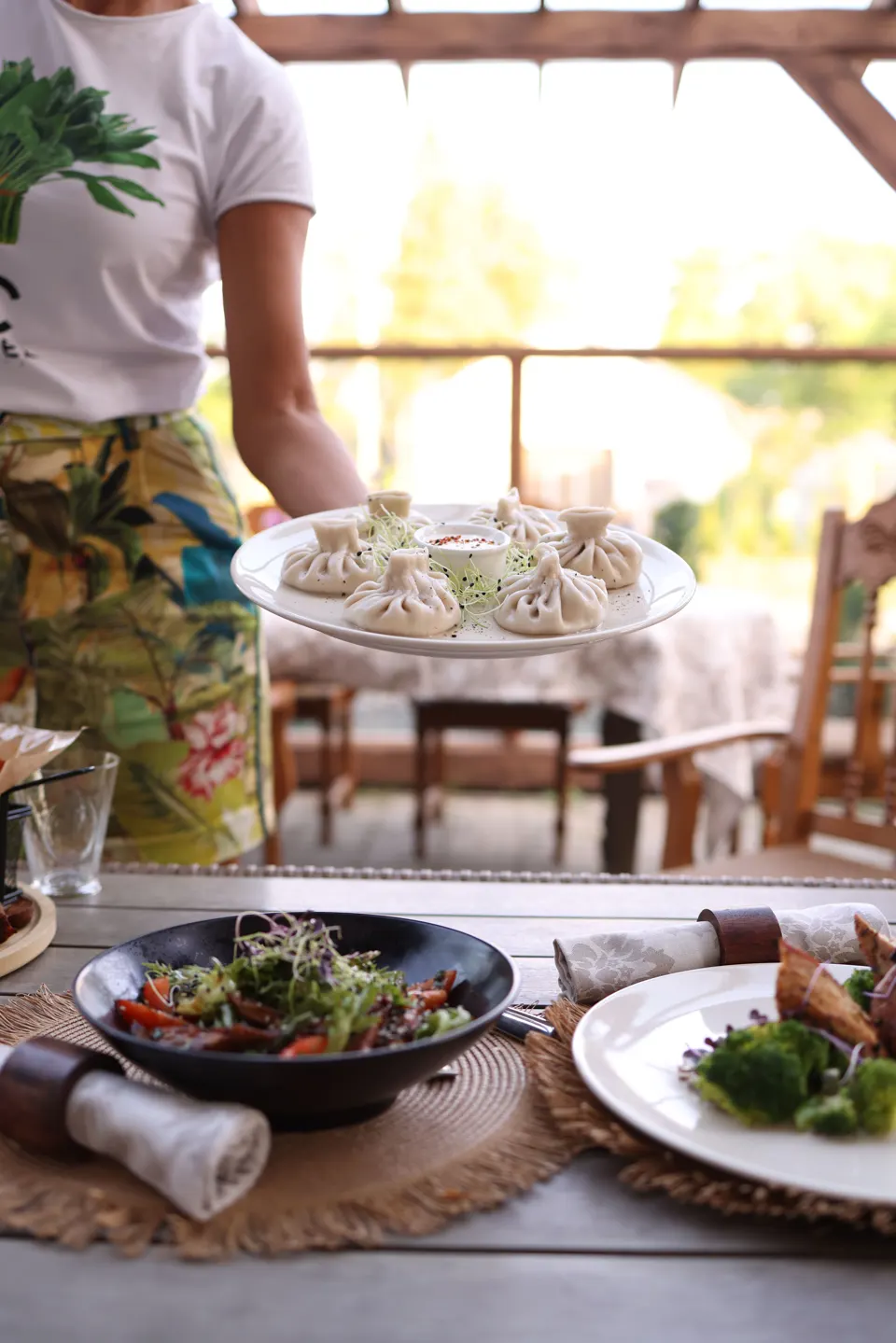 Server carrying a plate of khinkali at a Georgian restaurant
